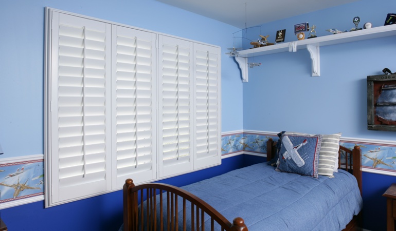 Large plantation shutters covering window in blue kids bedroom in Charlotte 